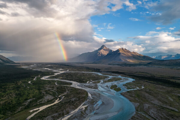 Carrying sediment that forms large, flat areas called alluvial plains over time, the winding channels of the Wind River flow through the valley towards a vibrant rainbow and Royal Mountain in the distance. Photo by Bethany Paquette.