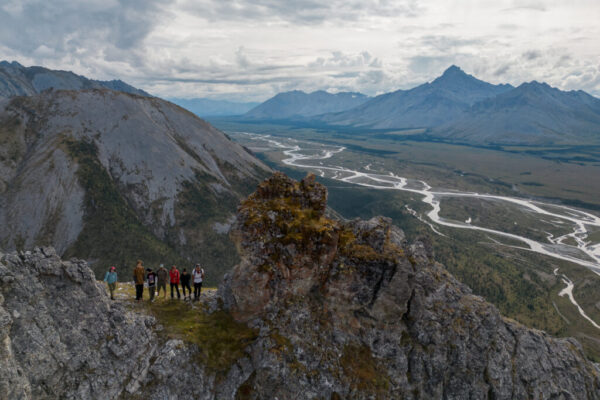 Aerial view of youth on a rocky ridge overlooking the Wind River, standing as part of the landscape like the plants and mountains nearby. Photo by Bethany Paquette.