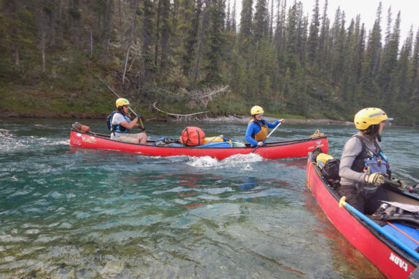 Paddling down the Wind River—Lucien steering the main canoe from the stern, Chantel in the bow, and Joti paddling in a separate canoe on the right.