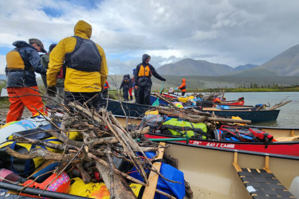 The group loads up canoes with gear and firewood to continue paddling down the Wind.