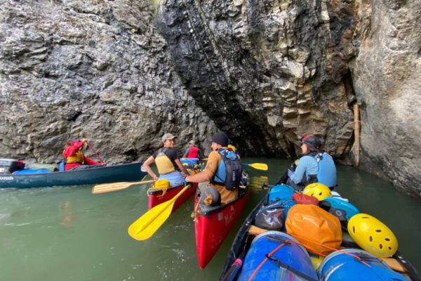 Shalaya, Virginia (stern), Joel (bow), Lucien, and Kadrienne (from left to right) gather in canoes at a cove found in the Peel canyon.