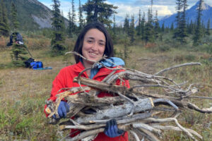 Kadrienne smiles while holding a bundle of firewood gathered for camp.