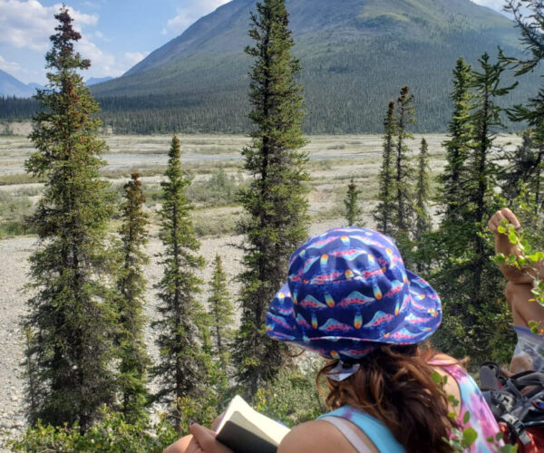 Shalayah sits among the trees, sketching mountains and overlooking the river.