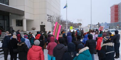 Fifty people stand in front of the Yukon Courts at the Whitehorse Peel Rally. Kwanlin Dün First Nation and the Ta’an Kwäch’än Council traditional territory, photo by Adil Darvesh.